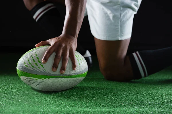 Desportista ajoelhado enquanto segurando bola de rugby — Fotografia de Stock
