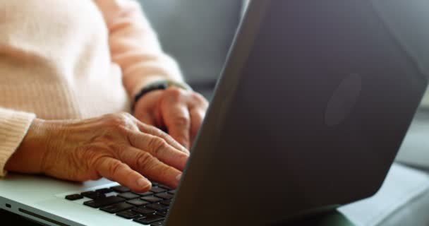 Senior kvinna använder laptop i vardagsrum — Stockvideo