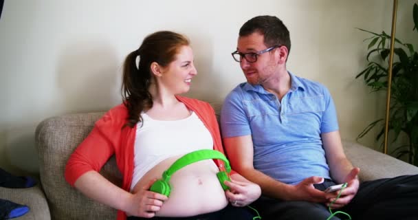Беременная женщина ставит наушники — стоковое видео