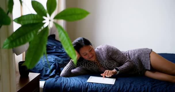 Женщина с помощью цифрового планшета во время отдыха на кровати — стоковое видео