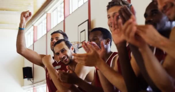 Emocionado jugador de baloncesto sentado en el banco y animando — Vídeos de Stock