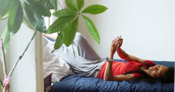 Жінка використовує мобільний телефон у спальні — стокове відео