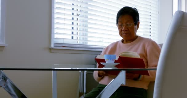 Senior woman reading book in living room — Stock Video