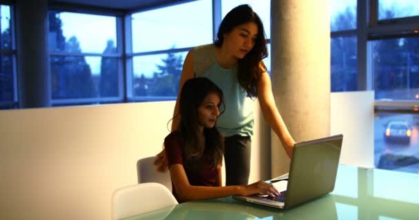Vrouwelijke leidinggevenden bespreken over laptop aan balie — Stockvideo