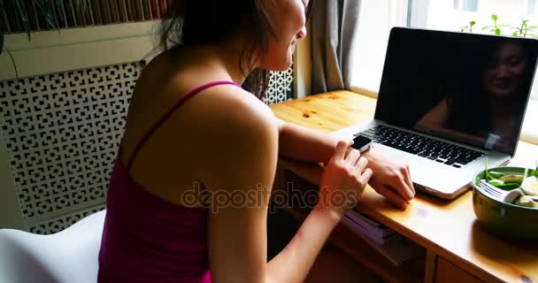 Mulher sentada à mesa e usando relógio inteligente — Vídeo de Stock