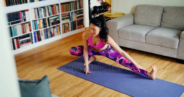 Beautiful woman practicing yoga in living room — Stock Video