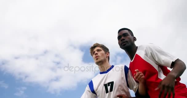 Два футболиста прыгают, чтобы ударить мячом — стоковое видео