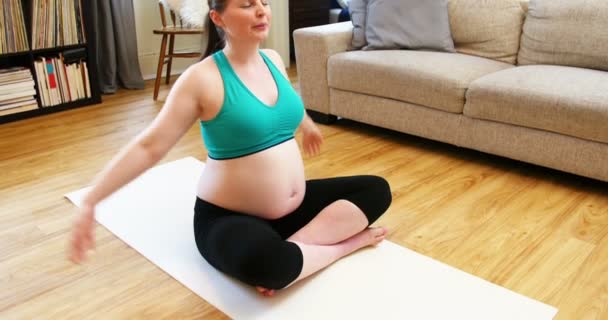 Беременная женщина практикует йогу в гостиной — стоковое видео