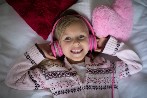Chica escuchando música en los auriculares mientras miente —  Fotos de Stock