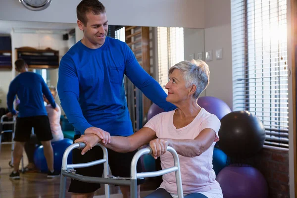 Fisioterapeuta auxiliando a paciente idosa a andar — Fotografia de Stock