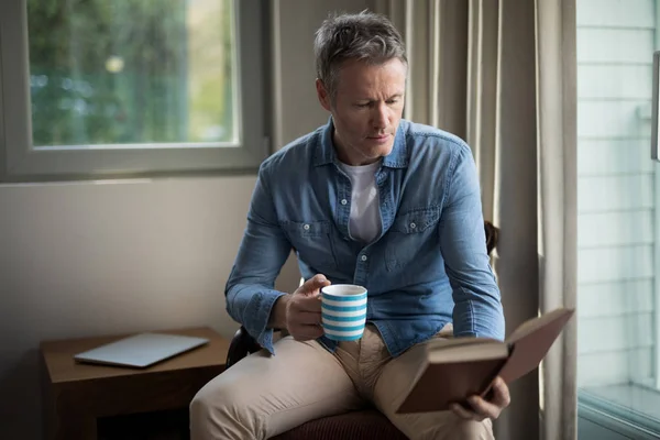 Man boek te lezen terwijl het hebben van koffie — Stockfoto