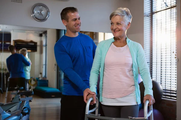 Physiotherapist assisting senior patient to walk — Stock Photo, Image