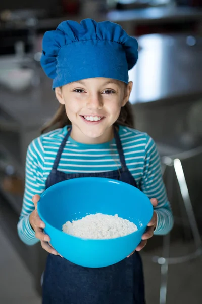 Menina segurando uma tigela de farinha na cozinha — Fotografia de Stock