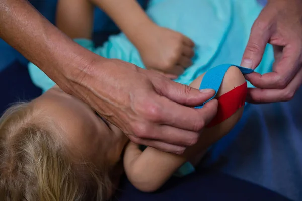 Fisioterapeuta pegando cinta adhesiva en paciente chica —  Fotos de Stock