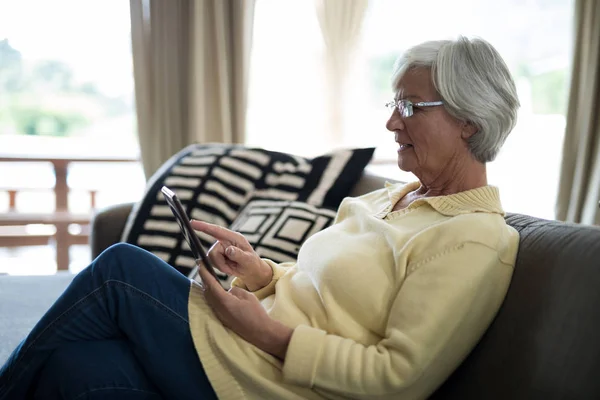 Senior woman using digital tablet on sofa — Stock Photo, Image