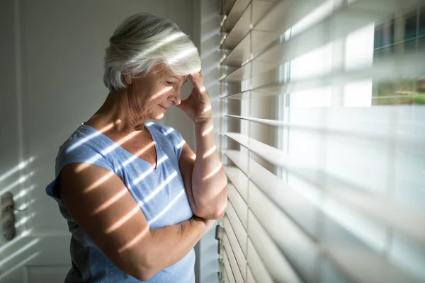 Napięta starszy Kobieta w pobliżu okna — Zdjęcie stockowe