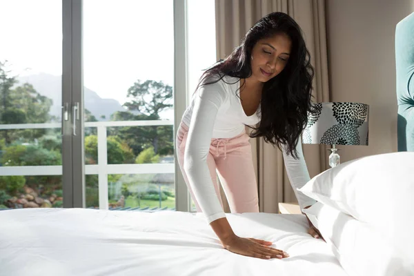 Jovem mulher fazendo cama em casa — Fotografia de Stock