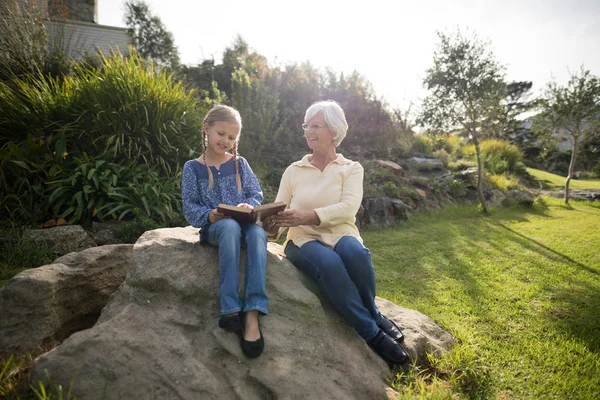 Petite-fille et grand-mère utilisant la tablette dans le jardin — Photo