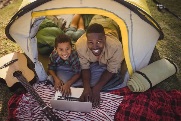 Père et fils utilisant un ordinateur portable dans la tente — Photo