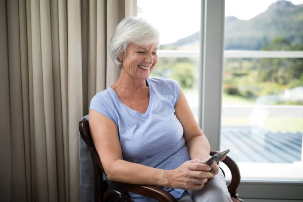 Senior woman using phone on chair — Stock Photo, Image