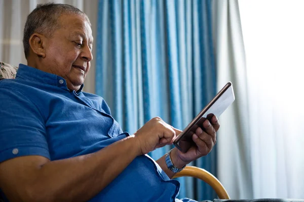 Uomo anziano utilizzando tablet digitale in casa di cura — Foto Stock