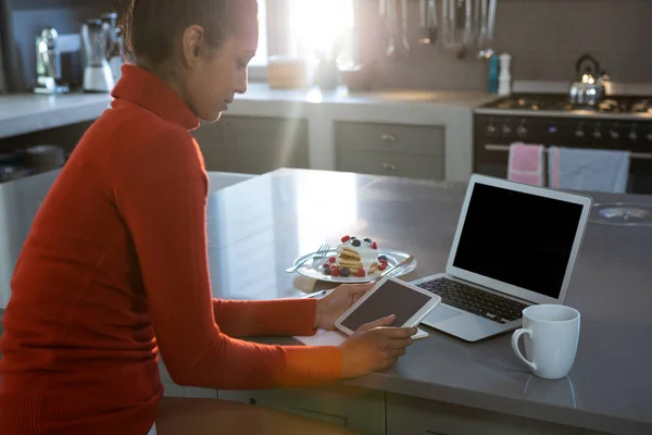 Woman using tablet at kitchen counter — Stock Photo, Image