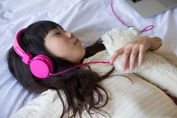 Lány az ágyon pihenés közben zenét hallgatni — Stock Fotó