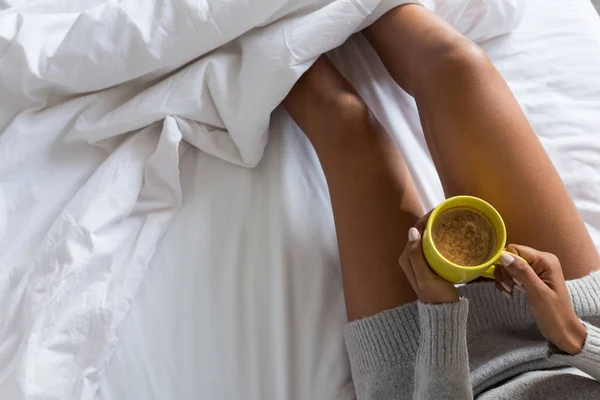 Mulher segurando caneca de café na cama — Fotografia de Stock