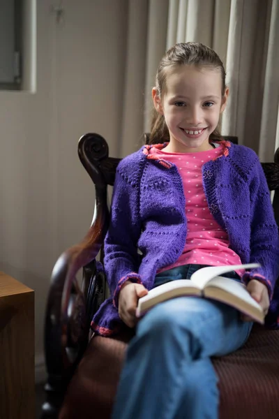 Sorridente ragazza lettura libro sulla sedia — Foto Stock