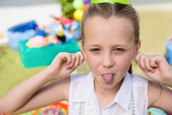 Flickan håller öronen samtidigt som sticker ut — Stockfoto