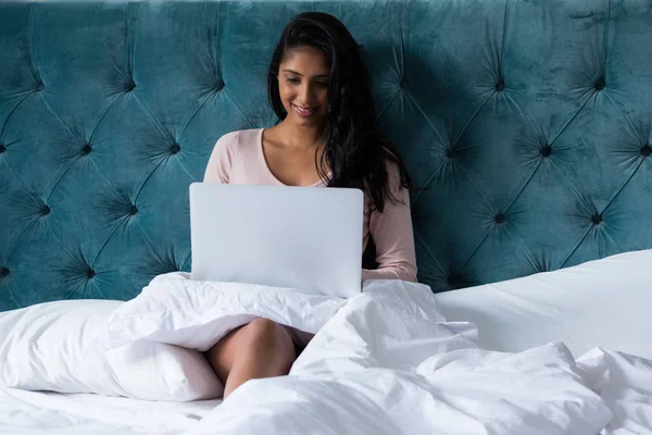 Жінка використовує ноутбук на ліжку — стокове фото