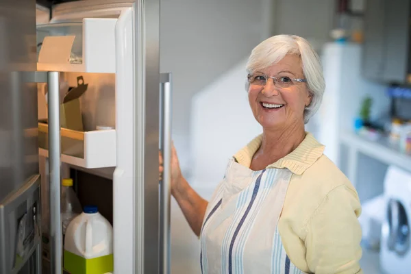 Усміхнені старші жінки відкривають холодильник — стокове фото