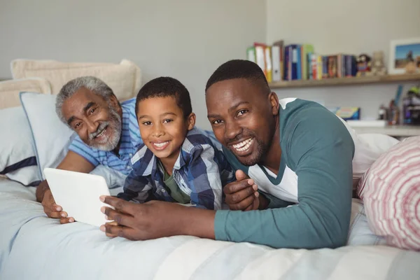 Mehrgenerationenfamilie mit Tablet im Bett — Stockfoto