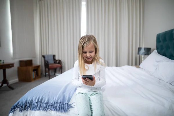 Meisje met telefoon op bed in de slaapkamer — Stockfoto