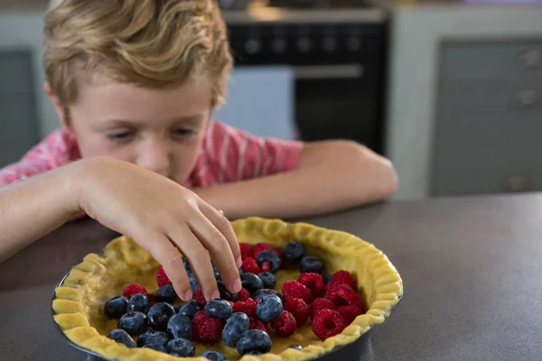 Junge bereitet in Küche Torte mit Beeren zu — Stockfoto