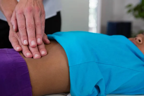 Физиотерапевт делает девушке массаж живота — стоковое фото