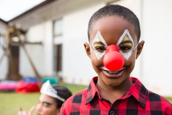 Niño con pintura facial con nariz de payaso —  Fotos de Stock