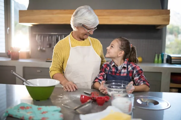 Grandmother and granddaughter holding bowl of flour — Stock Photo, Image