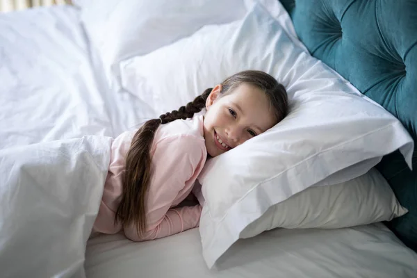 Chica sonriente acostada en la cama en el dormitorio —  Fotos de Stock