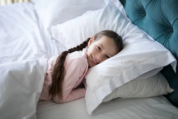 Chica sonriente acostada en la cama en el dormitorio — Foto de Stock