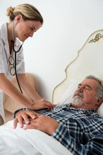 Doctor listening to heartbeats of man — Stock Photo, Image