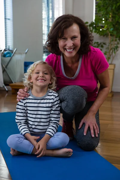 Улыбающаяся девушка и физиотерапевт на коврике для йоги — стоковое фото