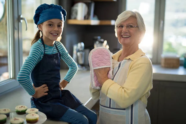 Oma en kleindochter met oven handschoenen — Stockfoto