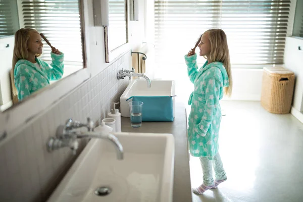 Chica peinándose el pelo en el baño — Foto de Stock