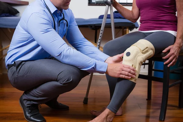 Fisioterapeuta examinando la rodilla de sus pacientes —  Fotos de Stock