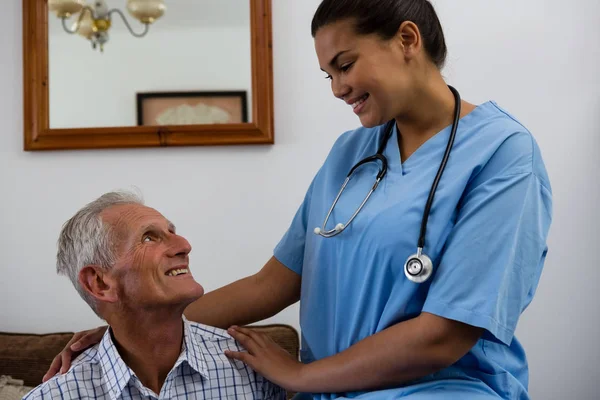 Medico donna consolante uomo anziano sul divano — Foto Stock