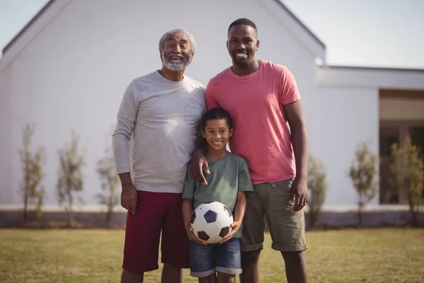 Сім'я, що стоїть в саду з футболом — стокове фото