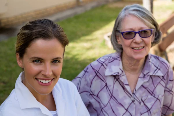 Medico sorridente con la donna anziana in cortile — Foto Stock