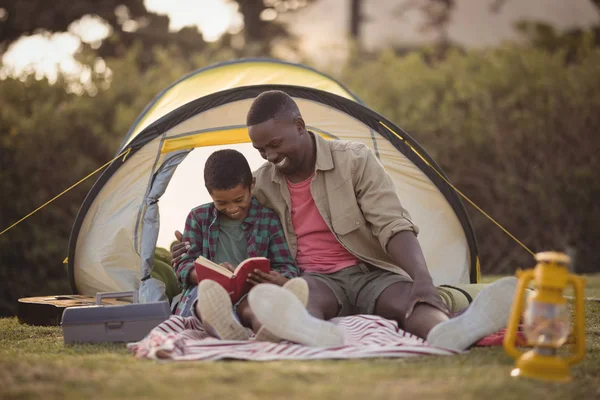 Padre e hijo leyendo libro en el parque — Foto de Stock