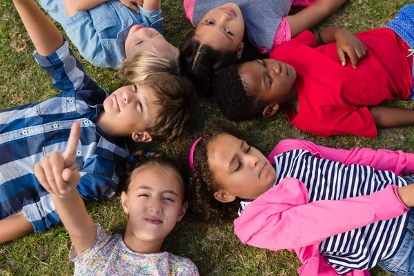 Kinderen met armen verhoogd liggend op veld — Stockfoto